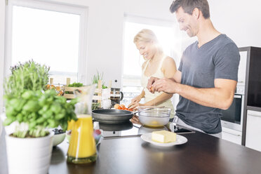 Couple preparing scrambled eggs together in the kitchen - MADF000225