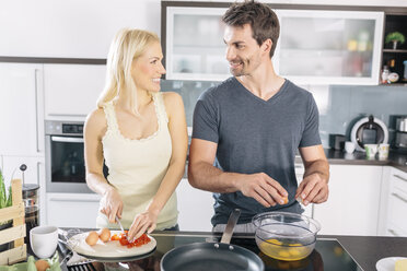 Couple preparing scrambled eggs together in the kitchen - MADF000227