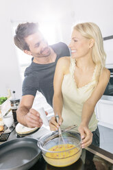 Ehepaar bereitet gemeinsam in der Küche Rührei zu - MADF000253