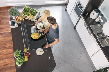 Couple preparing scrambled eggs together in the kitchen - MADF000259