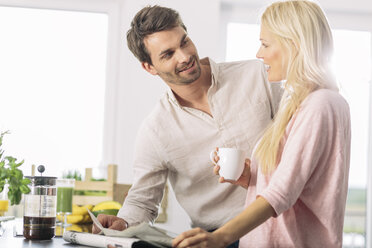 Ehepaar mit einer Tasse Kaffee und einer Zeitung in der Küche - MADF000295