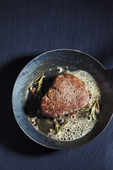 Gebratenes Rinderfilet mit Kräuterbutter, Pfefferkörnern und Rosmarin in einer Pfanne - CSF025493