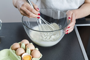 Woman stirring dough in a glassbowl with wire whisk - FLF001042