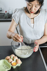 Woman stirring dough in a glassbowl with wire whisk - FLF001028