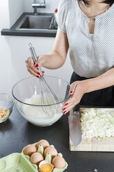 Woman stirring dough in a glassbowl with wire whisk - FLF001045