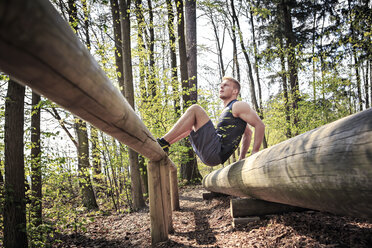 Deutschland, Coburg, Junger Mann beim Training auf einem Fitnessparcours im Wald - VTF000422