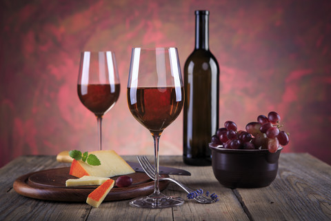 Stilleben mit Weinflasche, Weingläsern, Käse und Weintrauben, lizenzfreies Stockfoto