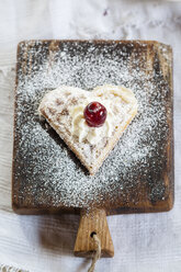 Herzförmige Waffel mit Schlagsahne und Kirsche auf Schneidebrett - SBDF001837