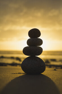 Spain, Galicia, Valdovino, Four small rocks in balance on the beach in backlight - RAEF000171