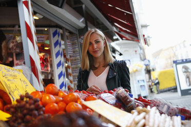 Porträt einer lächelnden blonden Frau auf dem Wochenmarkt - RHF000818