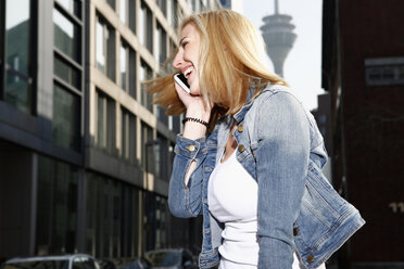 Deutschland, Düsseldorf, lachende blonde Frau beim Telefonieren mit Smartphone - RHF000839