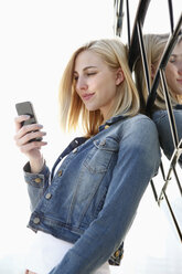 Germany, Duesseldorf, smiling blond woman looking at her smartphone - RHF000861