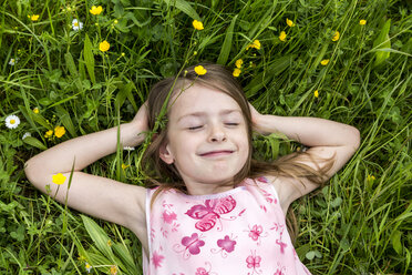 Portrait of smiling little girl with closed eyes lying on a flower meadow - SARF001776