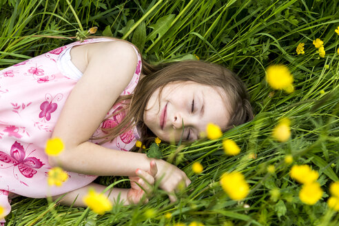 Lächelndes kleines Mädchen mit geschlossenen Augen auf einer Blumenwiese liegend - SARF001778