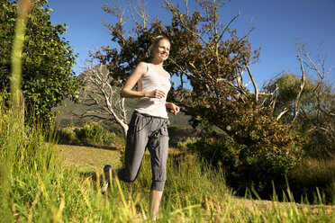 Smiling woman jogging in rural landscape - TOYF000333