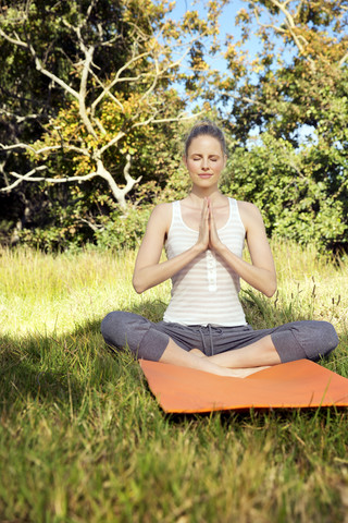 Frau übt Yoga auf einer Wiese, lizenzfreies Stockfoto