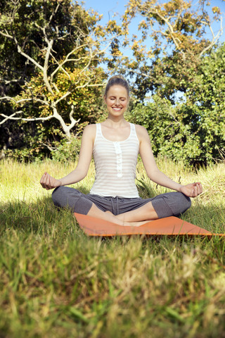 Smiling woman practising yoga in a meadow stock photo