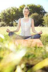 Woman practising yoga in a meadow - TOYF000342