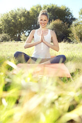 Frau übt Yoga auf einer Wiese - TOYF000343