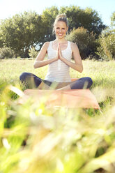 Woman practising yoga in a meadow - TOYF000343