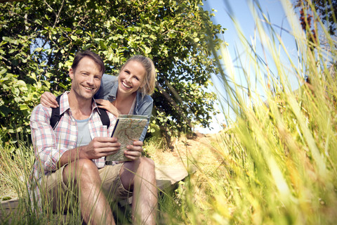 Glückliches Wanderpärchen mit Karte, das eine Pause einlegt, lizenzfreies Stockfoto