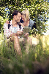 Happy hiking couple with map taking a break - TOYF000347