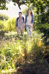 Lächelndes Paar beim Wandern Hand in Hand in ländlicher Landschaft - TOYF000394