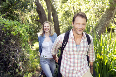 Lächelndes Paar beim Wandern Hand in Hand im Wald - TOYF000399