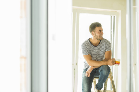 Junger Mann macht eine Kaffeepause vom Renovieren, lizenzfreies Stockfoto