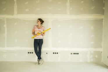 Junge Frau beim Renovieren an einer leeren Wand stehend - UUF004170
