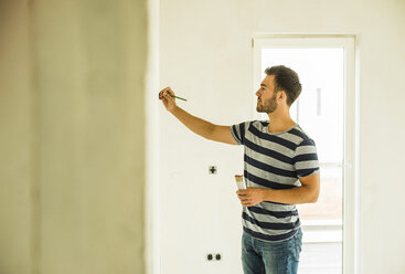 Young man renovating drawing marking at wall - UUF004178