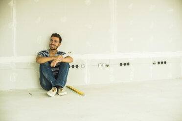 Young man renovating sitting at blank wall - UUF004183