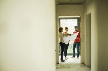 Architect showing construction plan to young couple - UUF004199