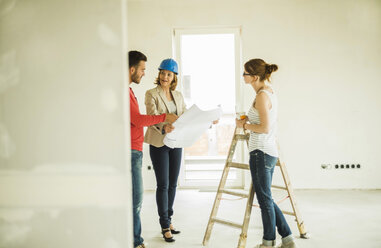 Architect showing construction plan to young couple - UUF004201