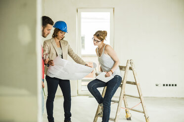 Architect showing construction plan to young couple - UUF004203