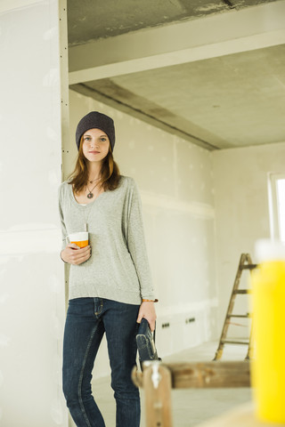 Junge Frau macht eine Kaffeepause beim Renovieren, lizenzfreies Stockfoto