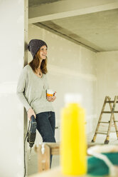 Smiling young woman having a coffee break from renovating - UUF004226