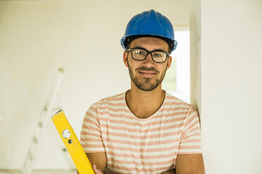 Portrait of smiling young man wearing hard hat - UUF004229