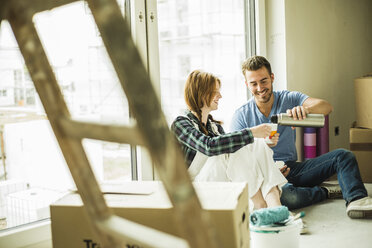 Smiling couple having a coffee break from renovating - UUF004245