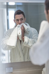 Spiegelbild eines Mannes, der sich beim Abtrocknen seines Gesichts mit einem Handtuch beobachtet - ZEF004685