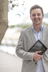 Porträt eines lächelnden Geschäftsmannes mit digitalem Tablet - ZEF005883