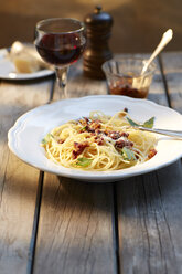 Dish of spaghetti with tomato pesto and grated parmesan and glass of red wine - KSWF001477