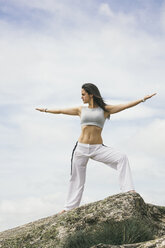 Woman doing yoga exercises on a mountain - ABZF000036