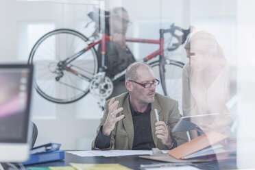 Geschäftsleute besprechen sich im Büro, im Hintergrund ist ein Fahrrad zu sehen - ZEF004915