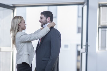 Businessman putting on a tie, woman assisting him - ZEF004923