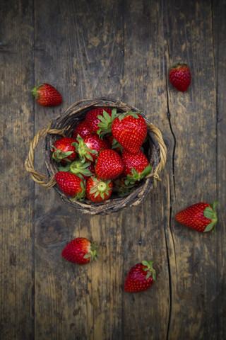 Weidenkorb mit Erdbeeren auf dunklem Holz, lizenzfreies Stockfoto