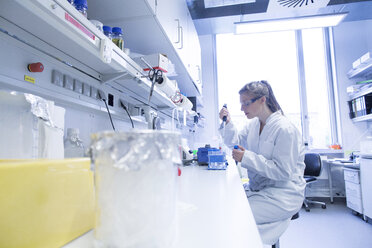 Young female scientist working at biological laboratory filling samples - SGF001574