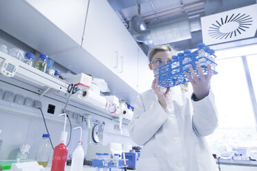 Young female scientist working at biological laboratory inspecting samples - SGF001575