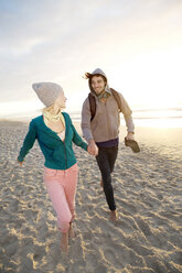 Junges Paar geht bei Sonnenaufgang am Strand spazieren - TOYF000414