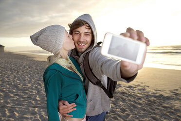 Junges Paar macht ein Selfie am Strand bei Sonnenaufgang - TOYF000416